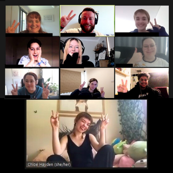 a screen shot of a group of people in an online meeting setting, smiling and laughing with some giving peace and thumbs up sign.