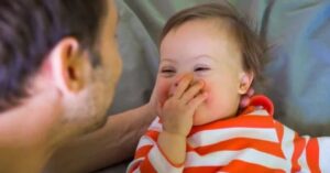 young baby laughing with hand over their mouth.