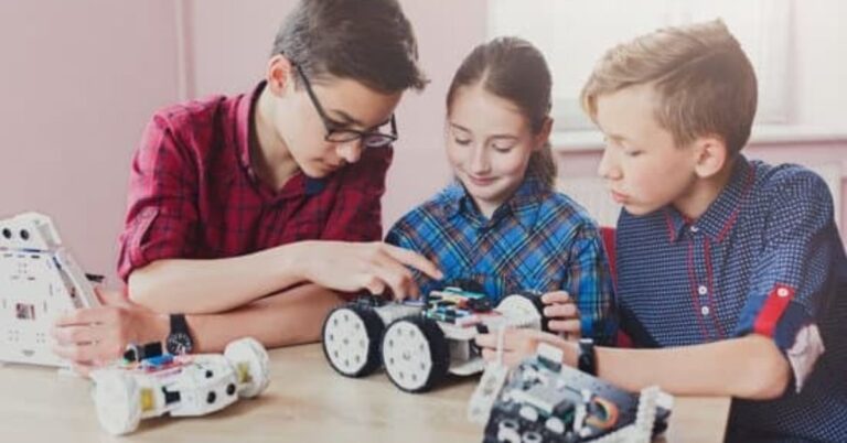 Three young people working on a stem project, building a robotic car.