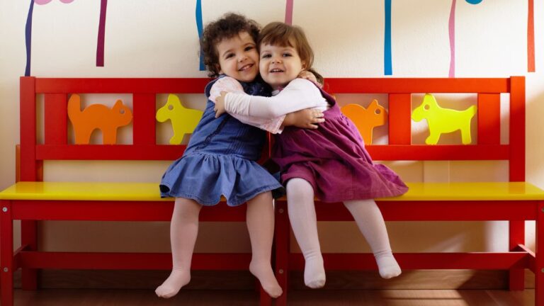 Two young girls hugging each other.