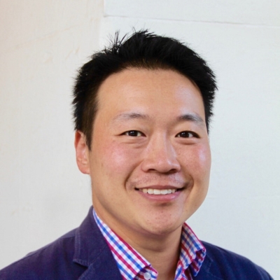 A profile picture of an asian man with short, black hair and a friendly smile. He is wearing a red and blue checked shirt with a blue blazer.