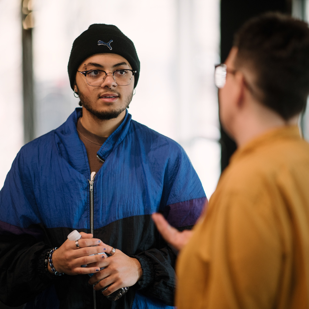 A young person wearing a beanie and a blue jacket having a discussion