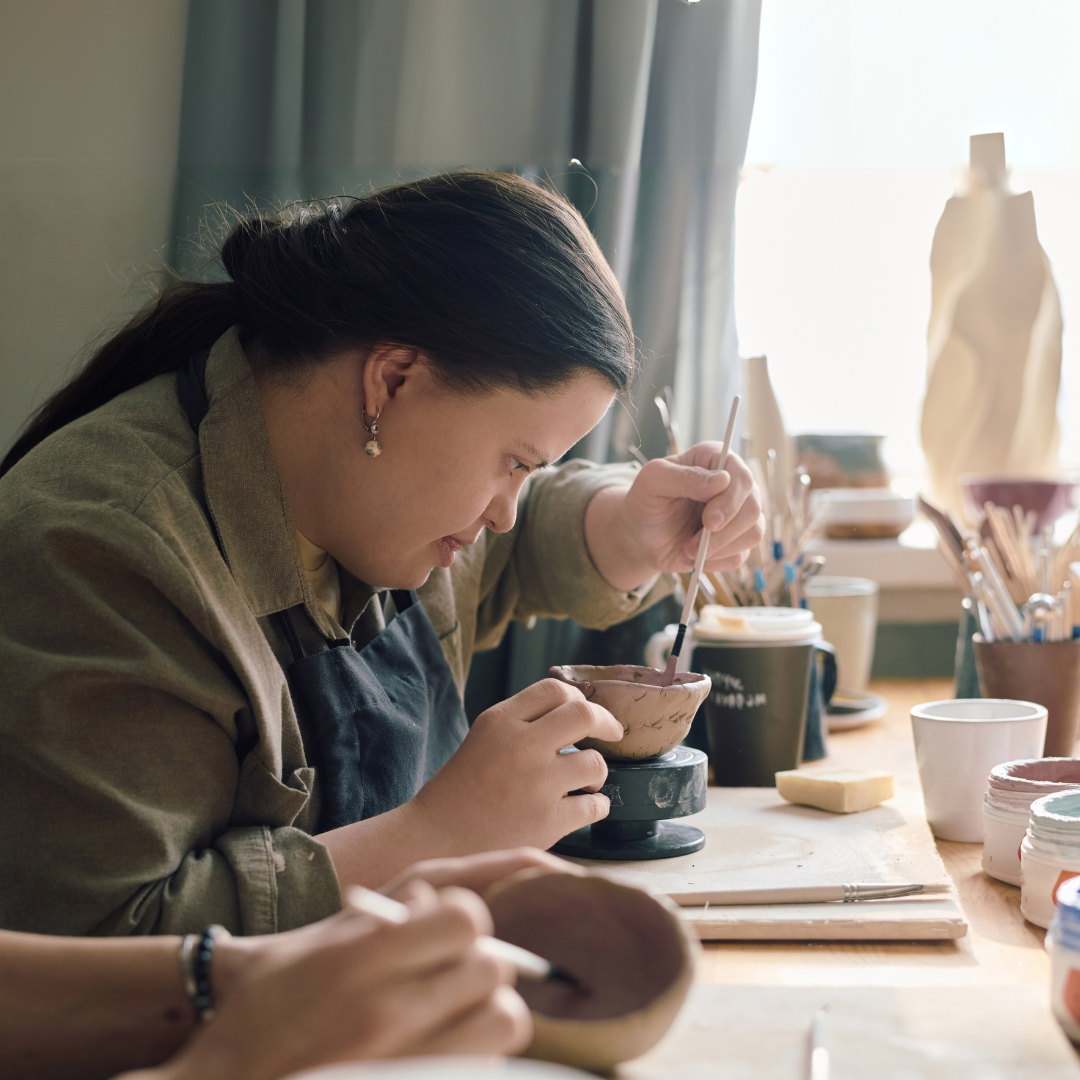 A young woman painting pottery