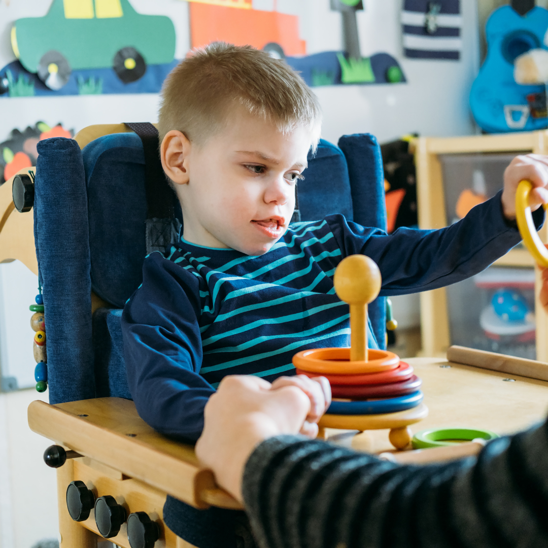 A young boy in a high chair playing with toys