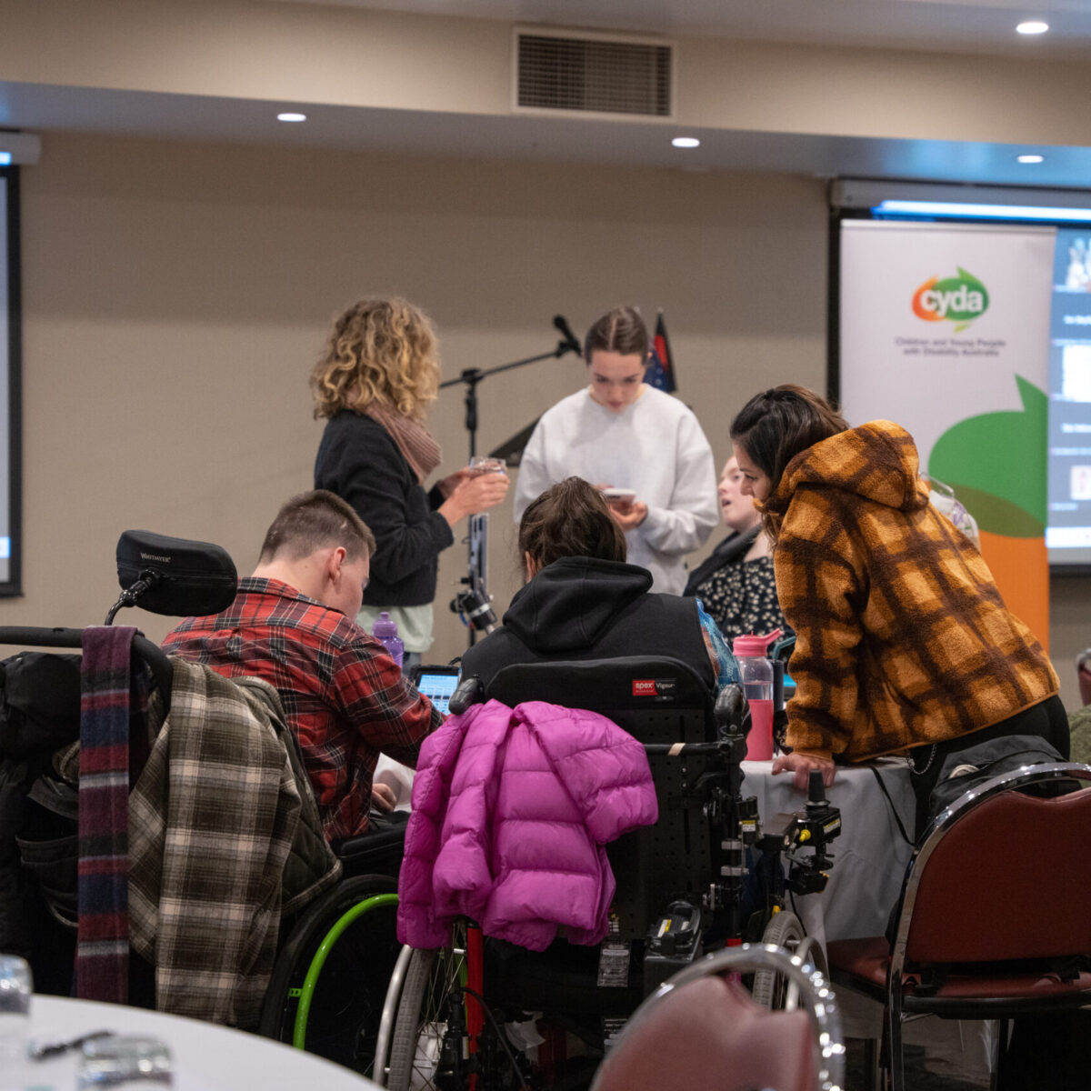 a group of young people with disability sit and stand together