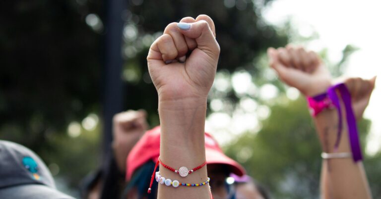 A photo of a fist being raised in the air at a protest march.